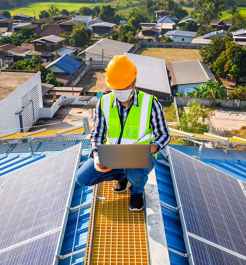 Engineers use a laptop computer to examine the solar panels on t Engineers use a laptop computer to examine the solar panels on the roof of a house where the solar panels are installed using solar energy.